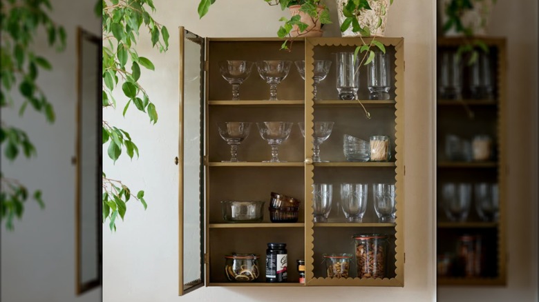 Magnolia glass cabinet hanging on wall with glasses inside