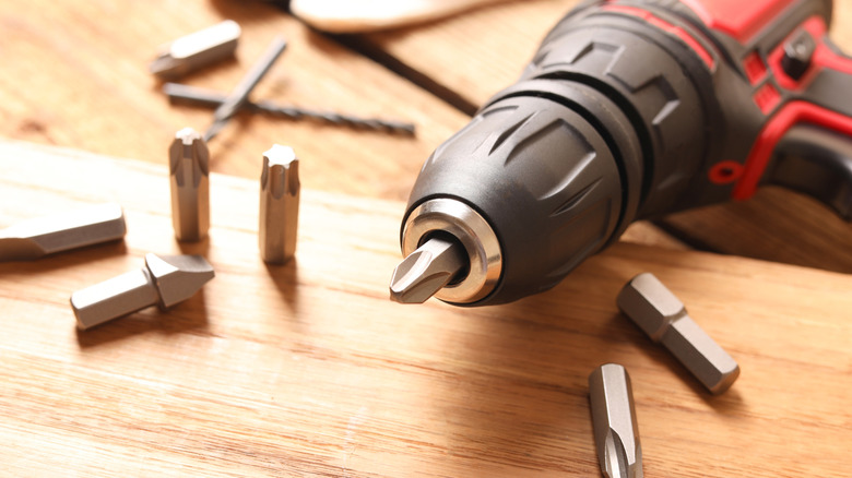 Electric screwdriver surrounded by disorganized screwdriver bits