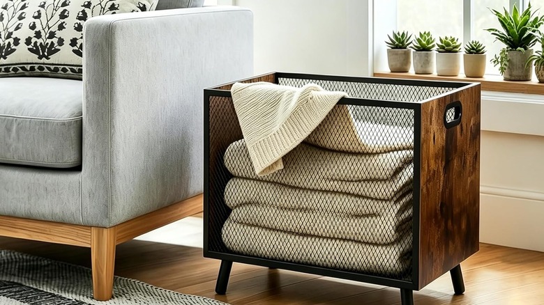 The FANTERSI Blanket Basket next to a couch with blankets in it