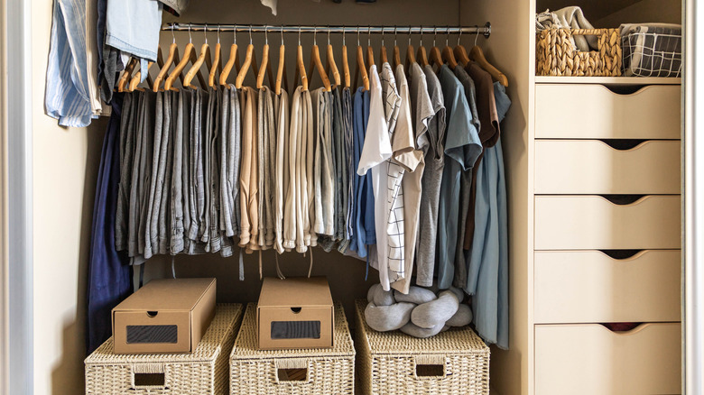 An organized closet uses woven wicker baskets on the floor to use overlooked storage space.
