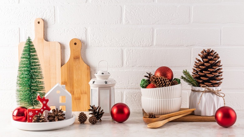 A holiday countertop scene with greenery, pinecones, and baubles
