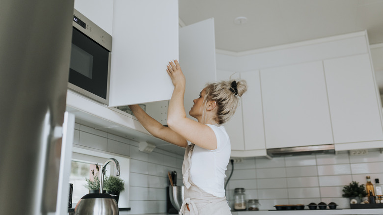 Woman opening a kitchen cabinet