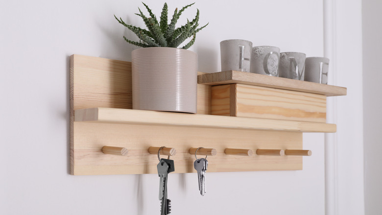 A wooden shelf with key hooks