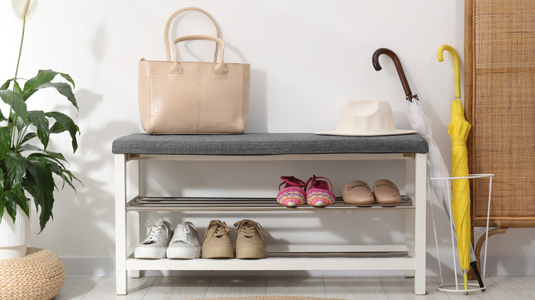 A shoe bench with shoes stored on the shelf beneath the seat