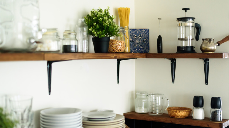 Dish and decorations on open wooden shelves in white kitchen