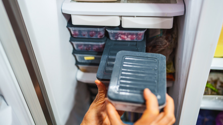 A woman organizes her plastic containers in a fridge
