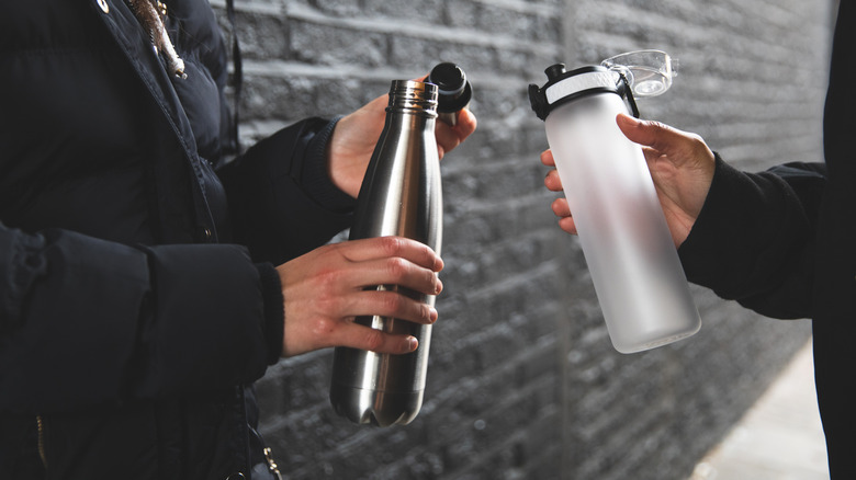 Two reusable tumblers being held by people
