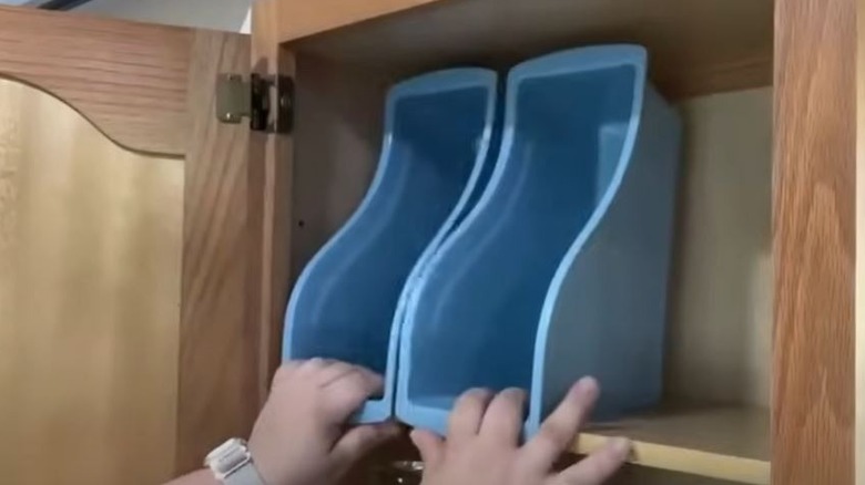 Woman placing Dollar Tree book bins in kitchen cabinet