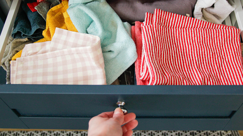 Person looking in disorganized kitchen towel drawer