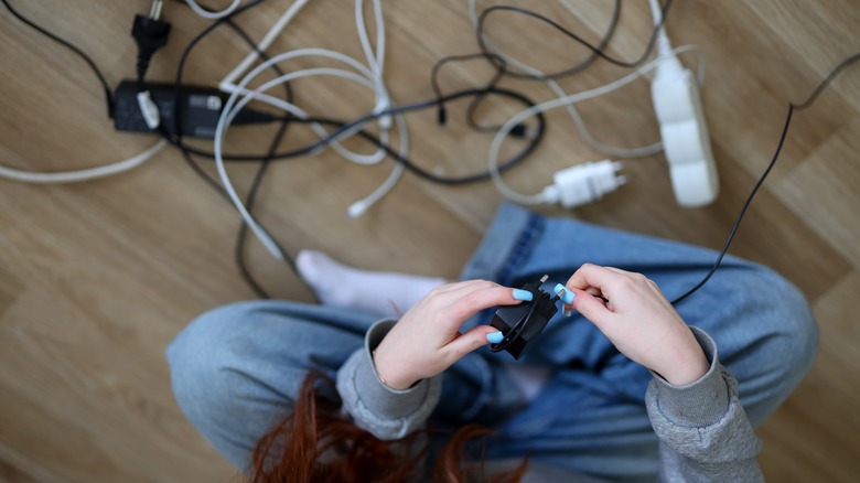 Girl wrapping a cord, with cords scattered all around the floor