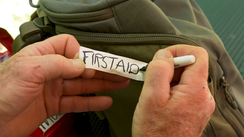 Person writing a first aid label for a backback