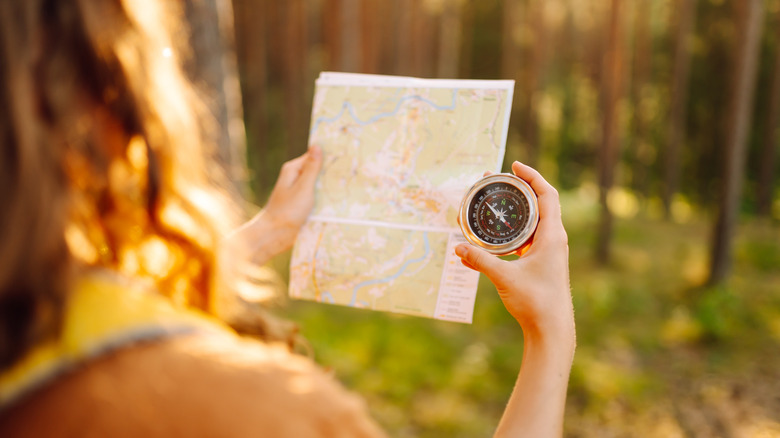 Woman holding a compass and a map
