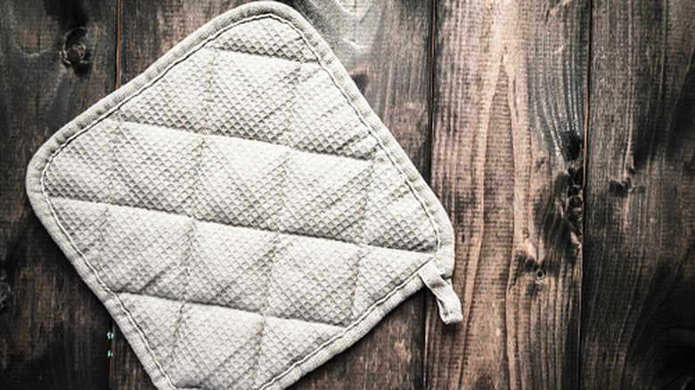 White-grey woven pot holder on a brown wooden surface