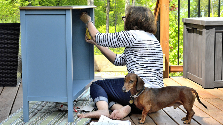 Woman assembling patio cabinet on deck.