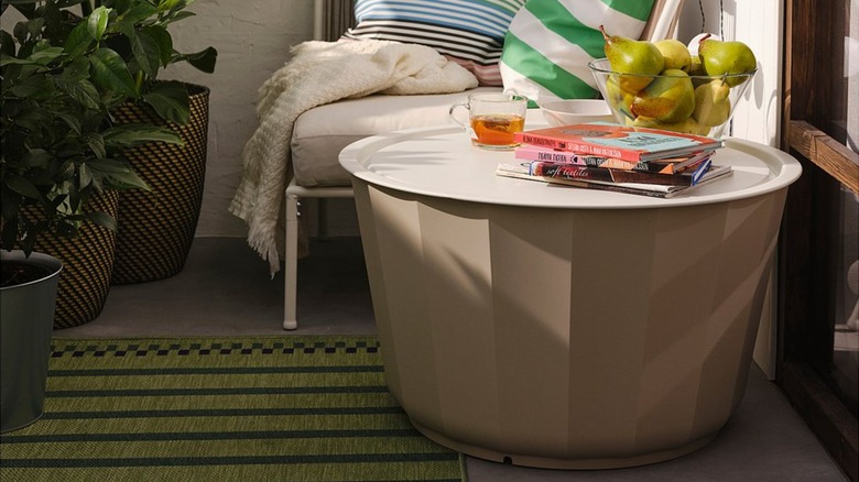 Round coffee table with books, bowl of pears, and mug of tea on top.