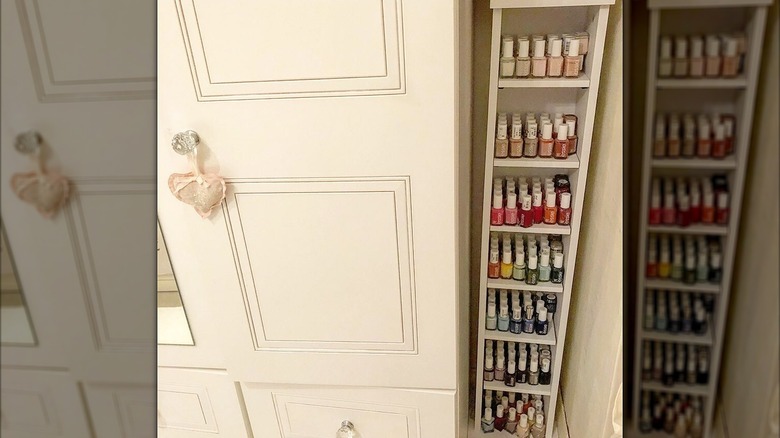 A narrow bookshelf in the corner of a room with nail polish on the shelves.