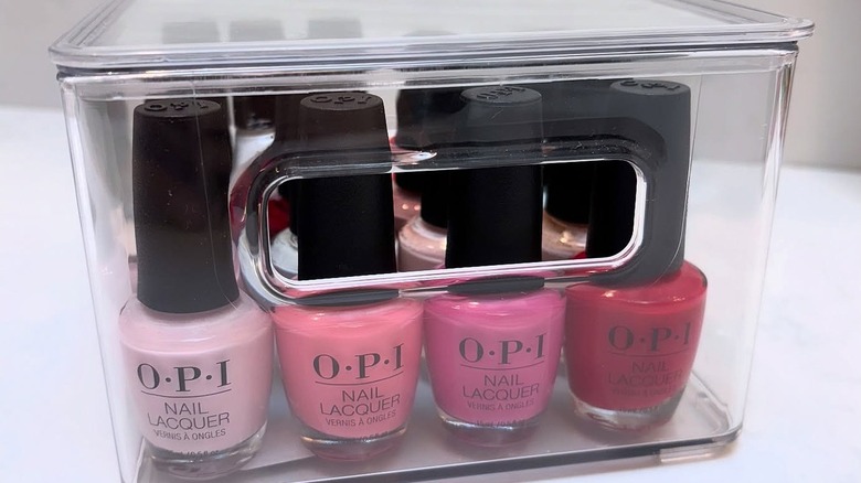 A lidded clear acrylic drawer with OPI nail polish bottles inside.