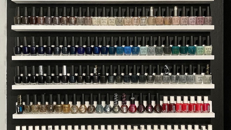 Floating shelves on a wall filled with bottles of nail polish.