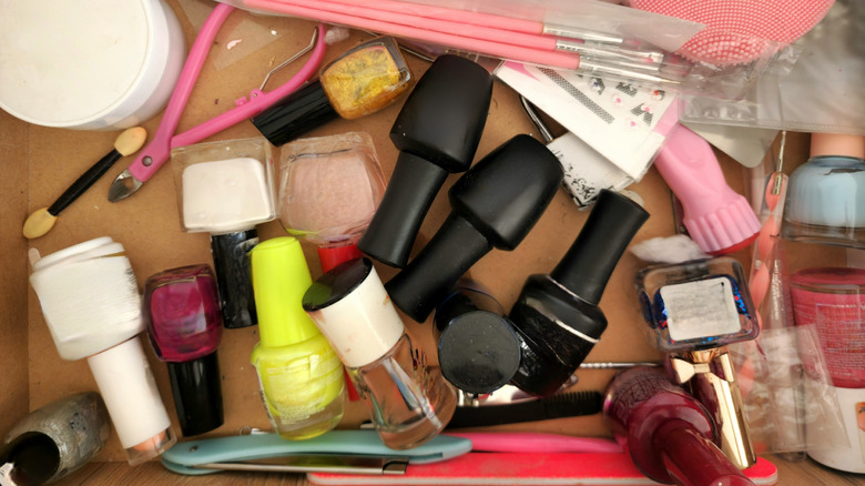 Nail polish bottles and tools lying haphazardly inside a cardboard box.