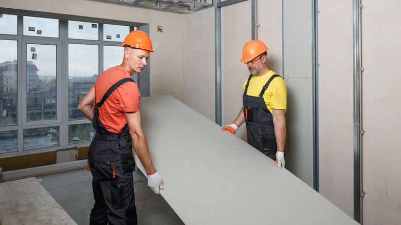 men carrying drywall sheets