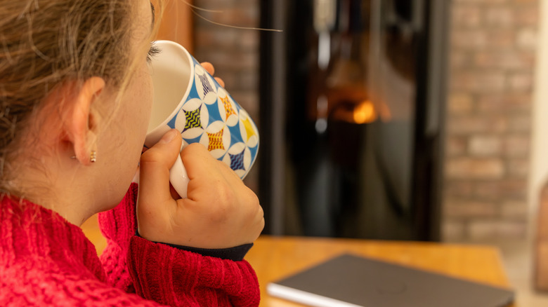woman warming herself in front of a wood pellet fire place