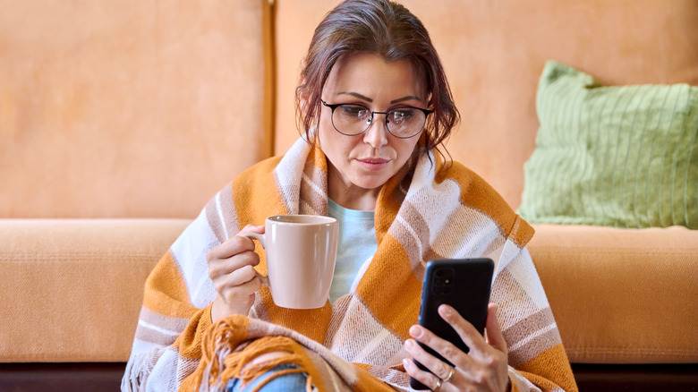 woman wrapped in blanket with a warm beverage