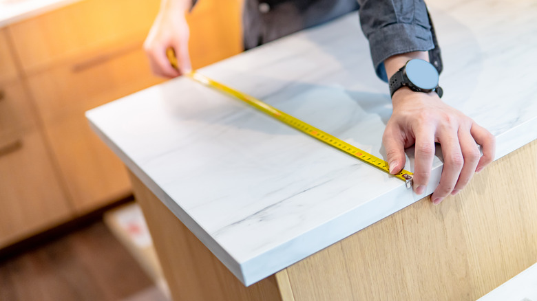 Person measuring kitchen island 