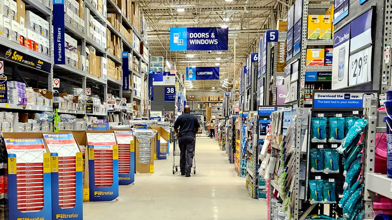 Shopper with cart in the aisle of a Lowe's store.