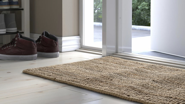A woven IKEA LOHALS door mat by a door