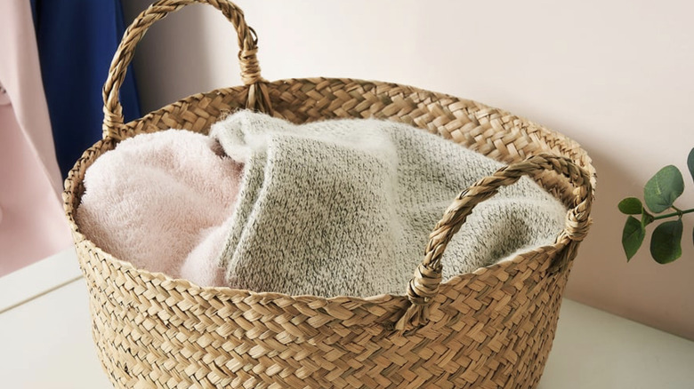 A woven SANDJORD basket holding soft blankets