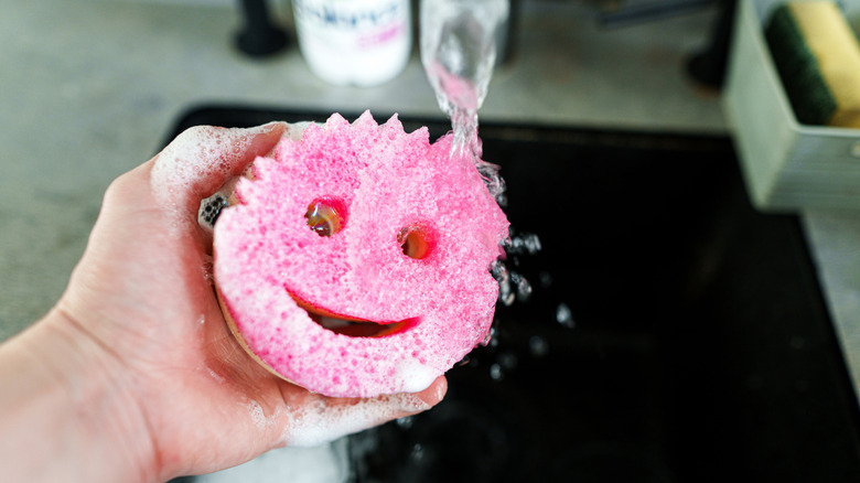 Scrub Daddy sponge being rinsed in a sink