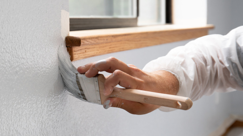 person painting edge of windowsill