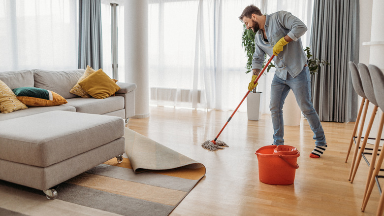 Person cleaning under rug