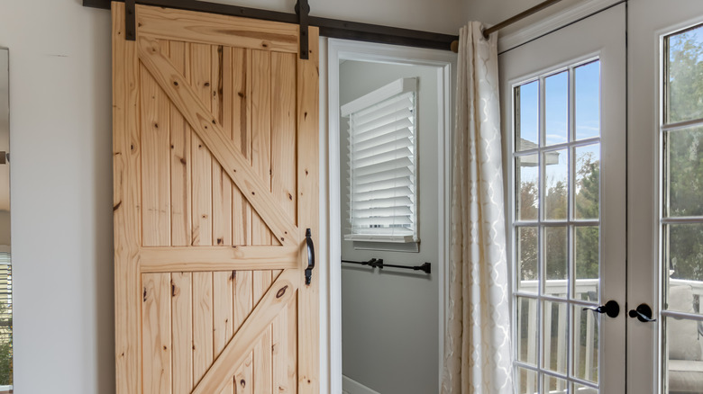 A barn door hung in front of an ensuite bathroom