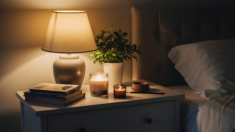 nightstand with books, candles, and lamp