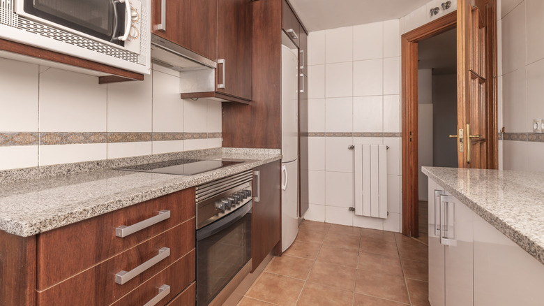 An outdated kitchen with warm wood countertops and brown-gray granite