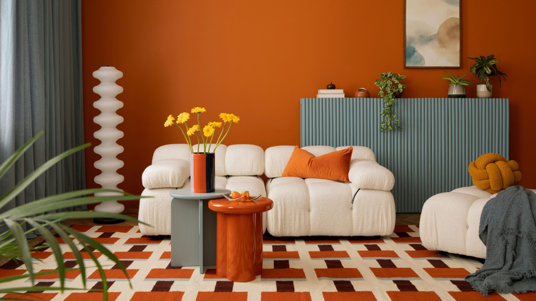 Contemporary orange maximalist interior with modern white couch
