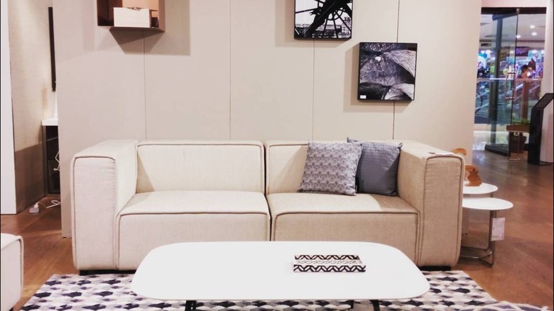 White boxy sofa in a living room with white coffee table and art on a wall