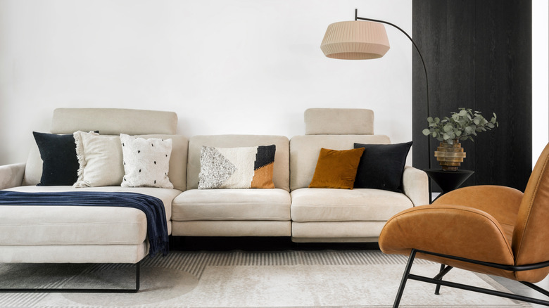 A modern living room with a sectional sofa, contemporary lamp, and plush chair
