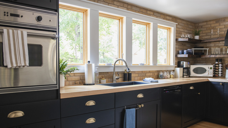Modern kitchen with black cabinets and brick walls