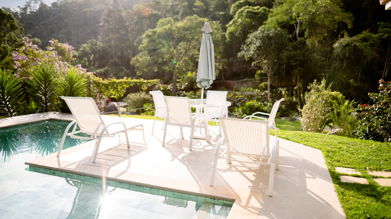 Matching white patio furniture set up near a pool