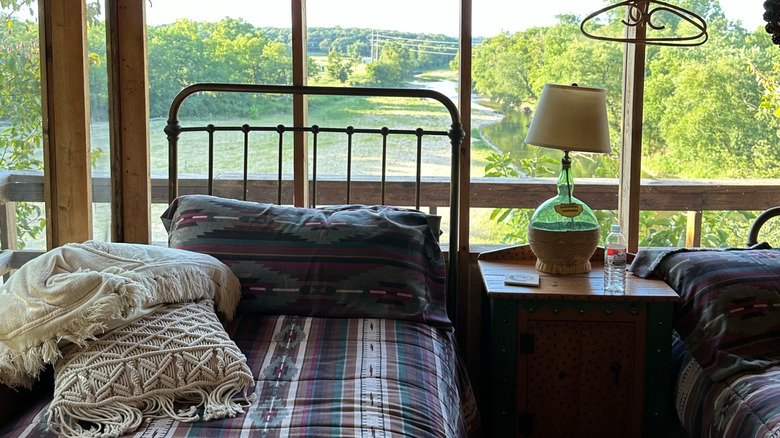 A cabin-style screened sleeping porch with a few beds and other furniture.