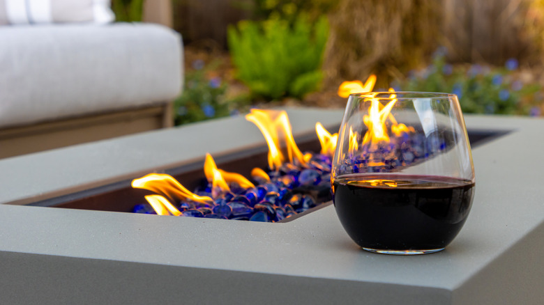 A firepit table with a glass of wine