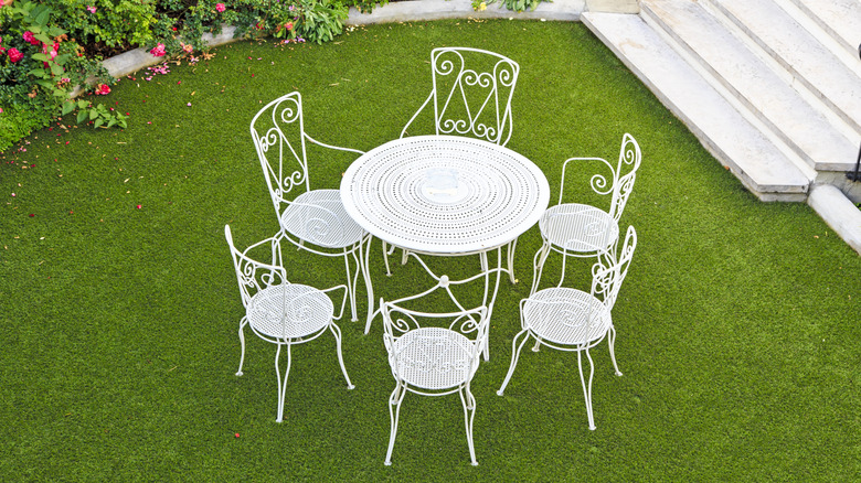 A white metal outdoor furniture set of chairs and a table on a green lawn