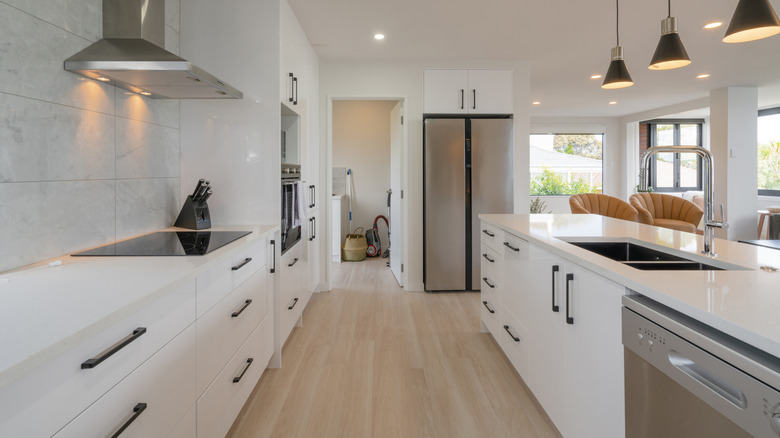 An all-white narrow kitchen.
