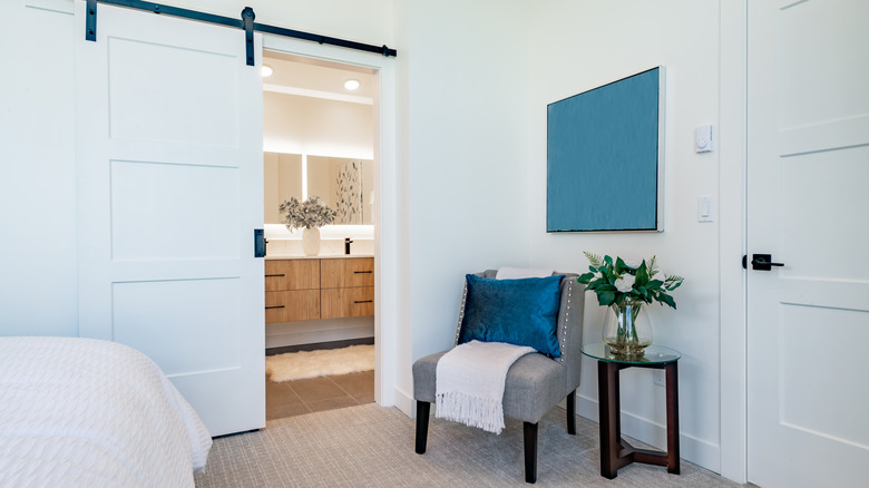 A partially opened barn door leading to an en-suite bathroom.