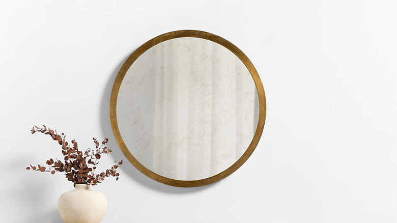 A round mirror with patina hanging on the wall.