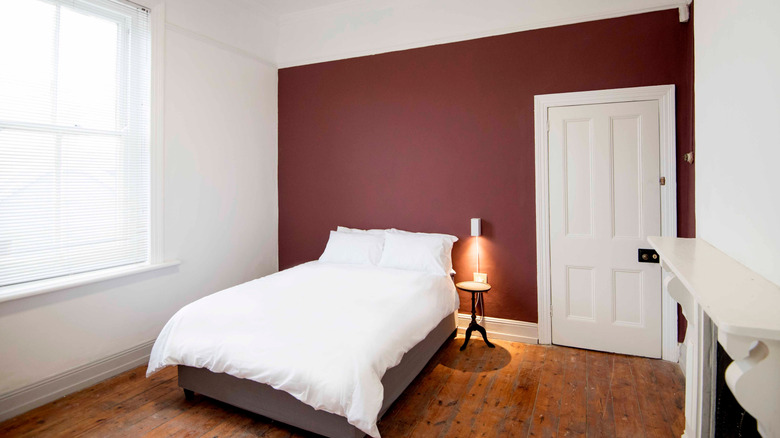 A bedroom with a maroon accent wall.