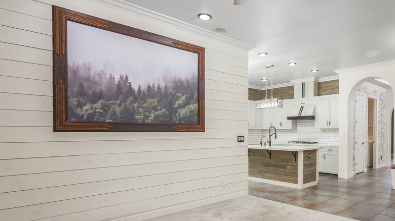A shiplap wall with a modern kitchen in the background.