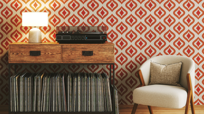 A record player on a credenza with geometric mod wallpaper.